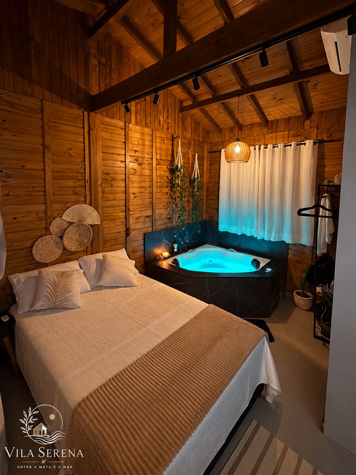 Estúdio 1: cama de casal com a banheira de hidromassagem acesa em azul ao fundo