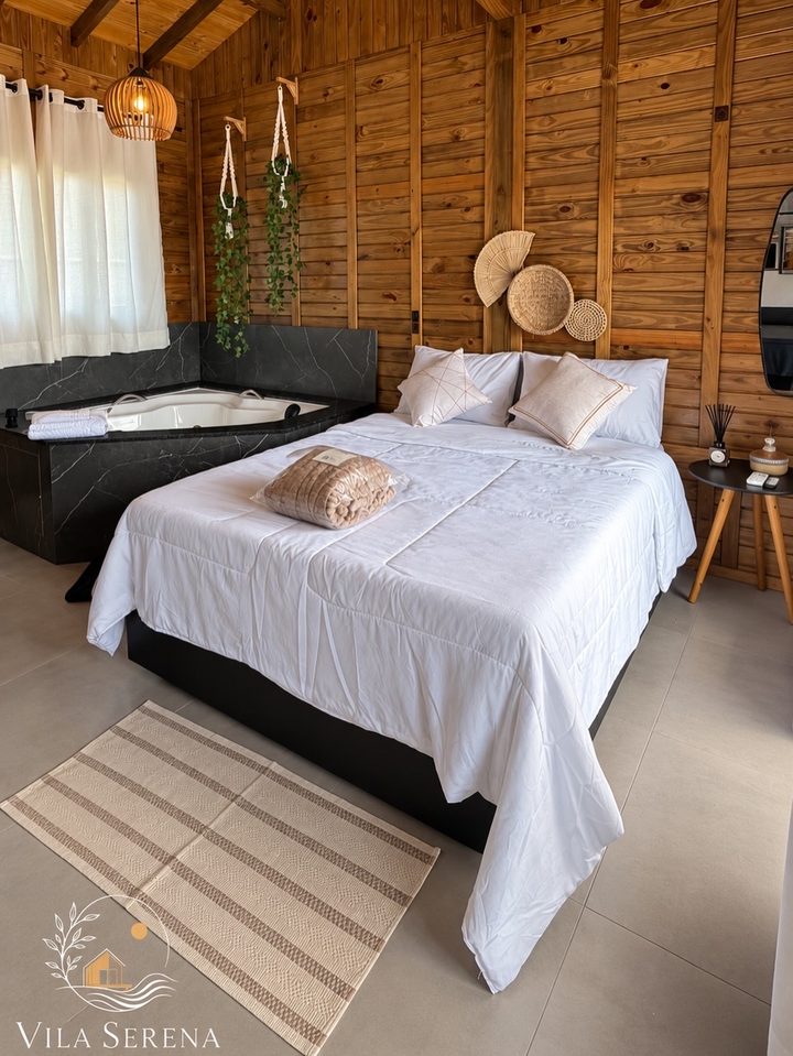 Estúdio 2: cama de casal com roupa branca e a banheira de hidromassagem ao lado